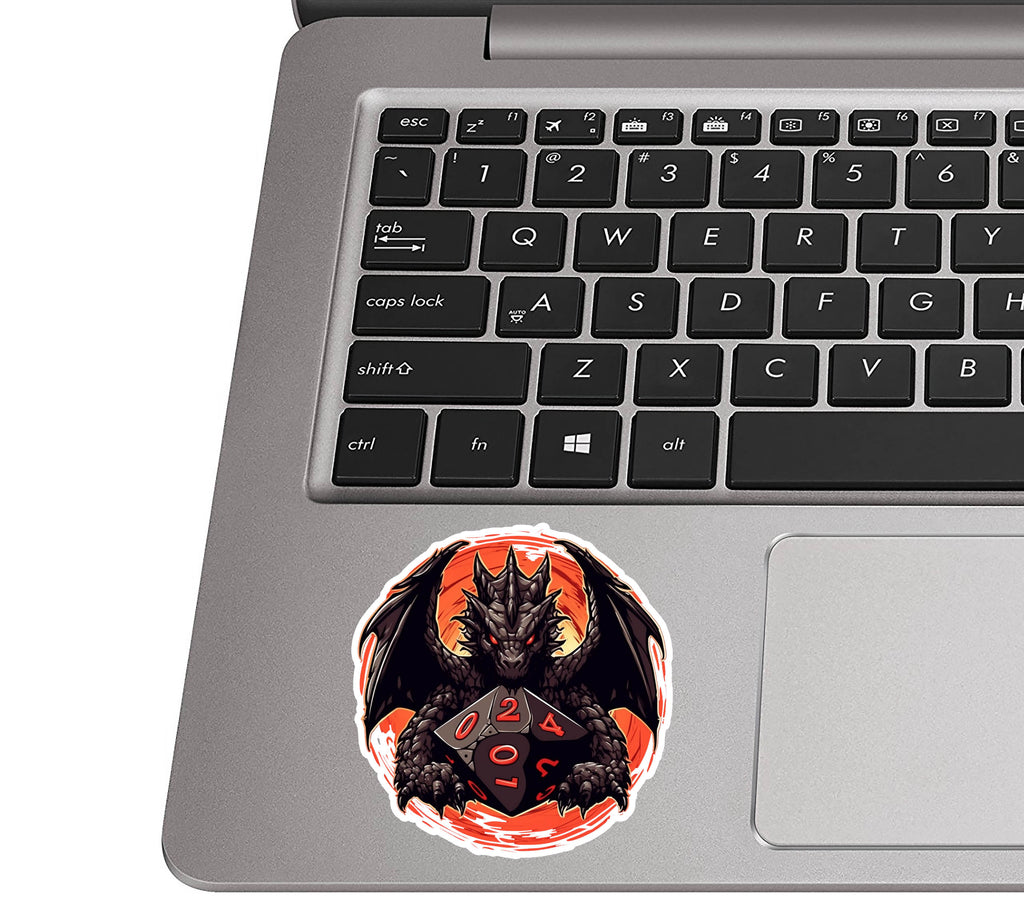 Dragon-and-D20 dice sticker placed on a silver laptop palm rest near a black QWERTY keyboard for size context
