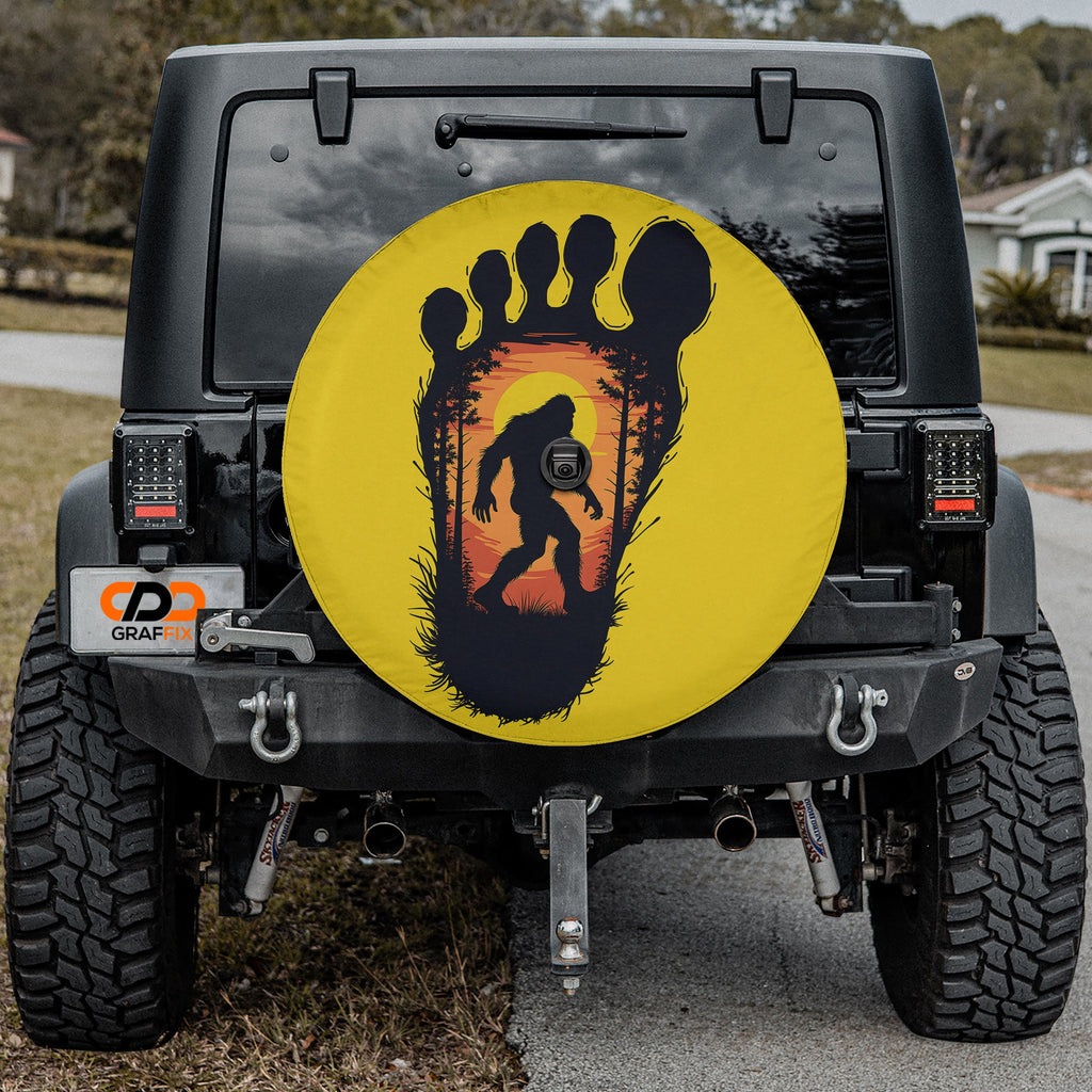 Squatch Track spare tire cover on red Jeep Wrangler featuring Bigfoot inside footprint graphic
