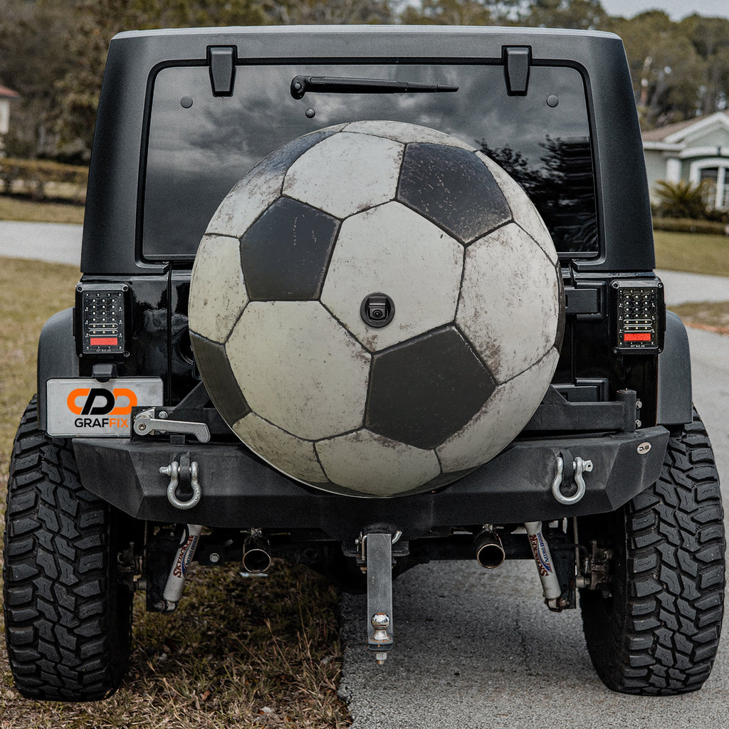 Soccer ball black and white spare tire cover mounted on black Jeep Wrangler rear outdoors