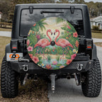 a black Jeep Wrangler with a large, colorful wheel cover depicting a tropical scene with two pink flamingos standing in a pond surrounded by lush greenery.