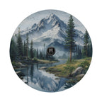 A serene landscape featuring a mountain range, pine trees, a river, and a forest, with a black camera lens in the center of the image.
