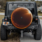 a black Jeep Wrangler with a large orange spare tire attached to the rear of the vehicle.