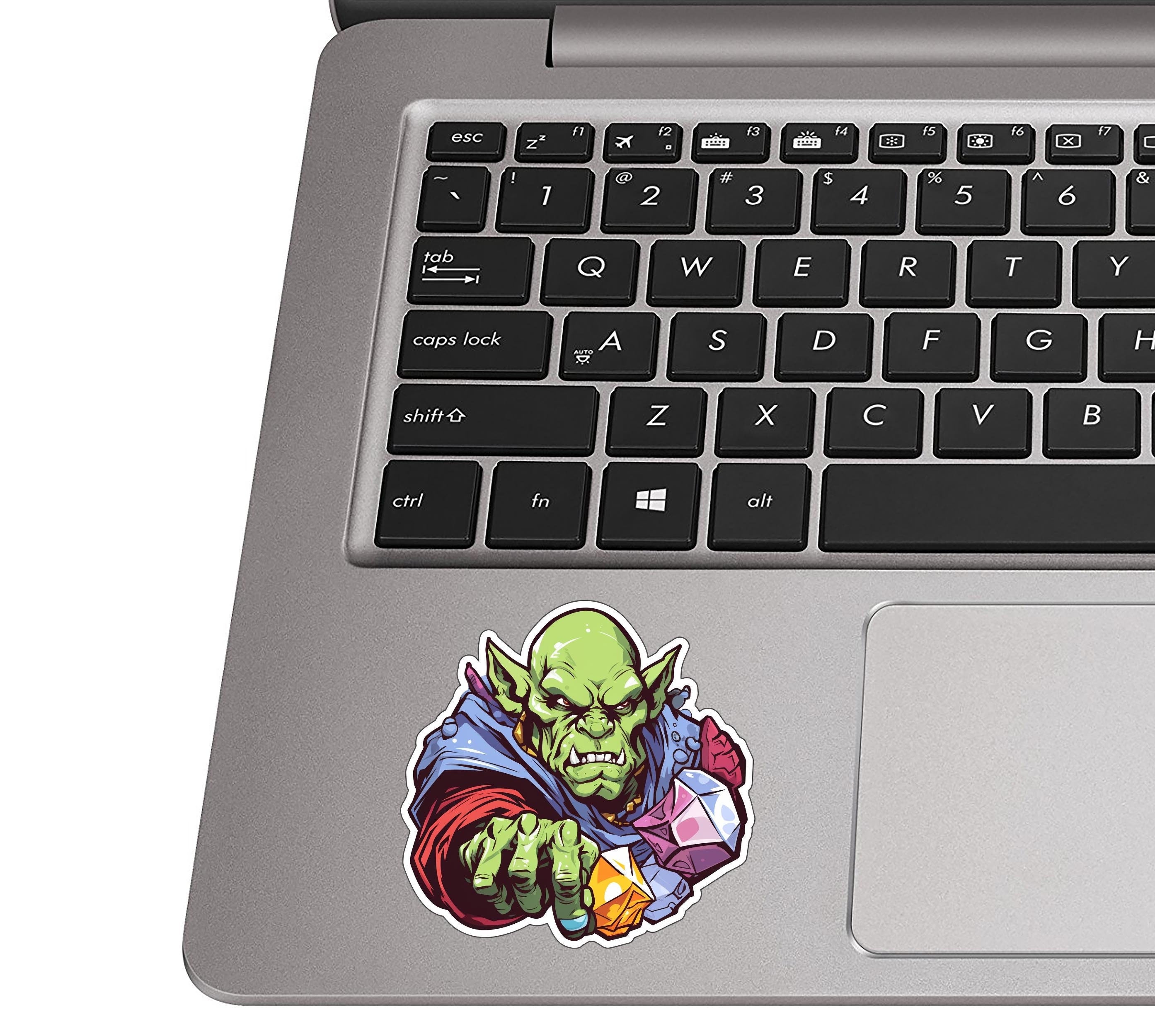 Goblin lord with gems decal on a silver laptop palm rest beside a black QWERTY keyboard for realistic size view