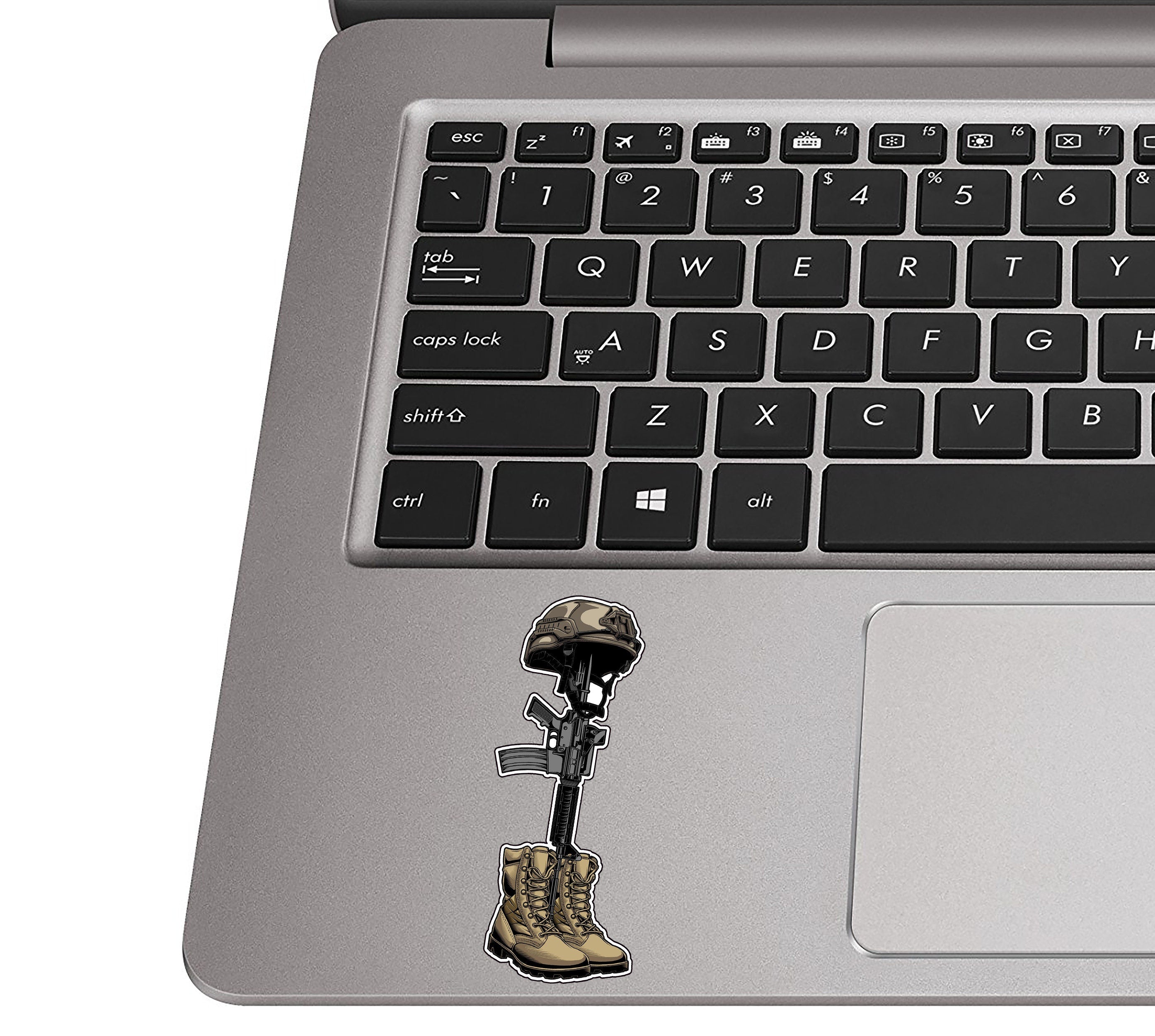 Fallen-soldier battlefield-cross decal applied to a silver laptop palm rest beside a QWERTY keyboard for scale
