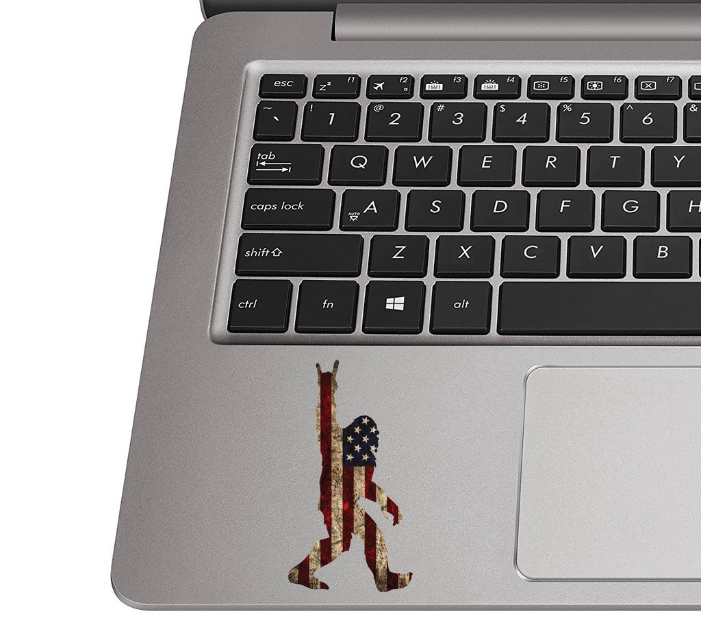 Rock On Sasquatch flag sticker on a silver laptop palm rest near a black QWERTY keyboard for scale view