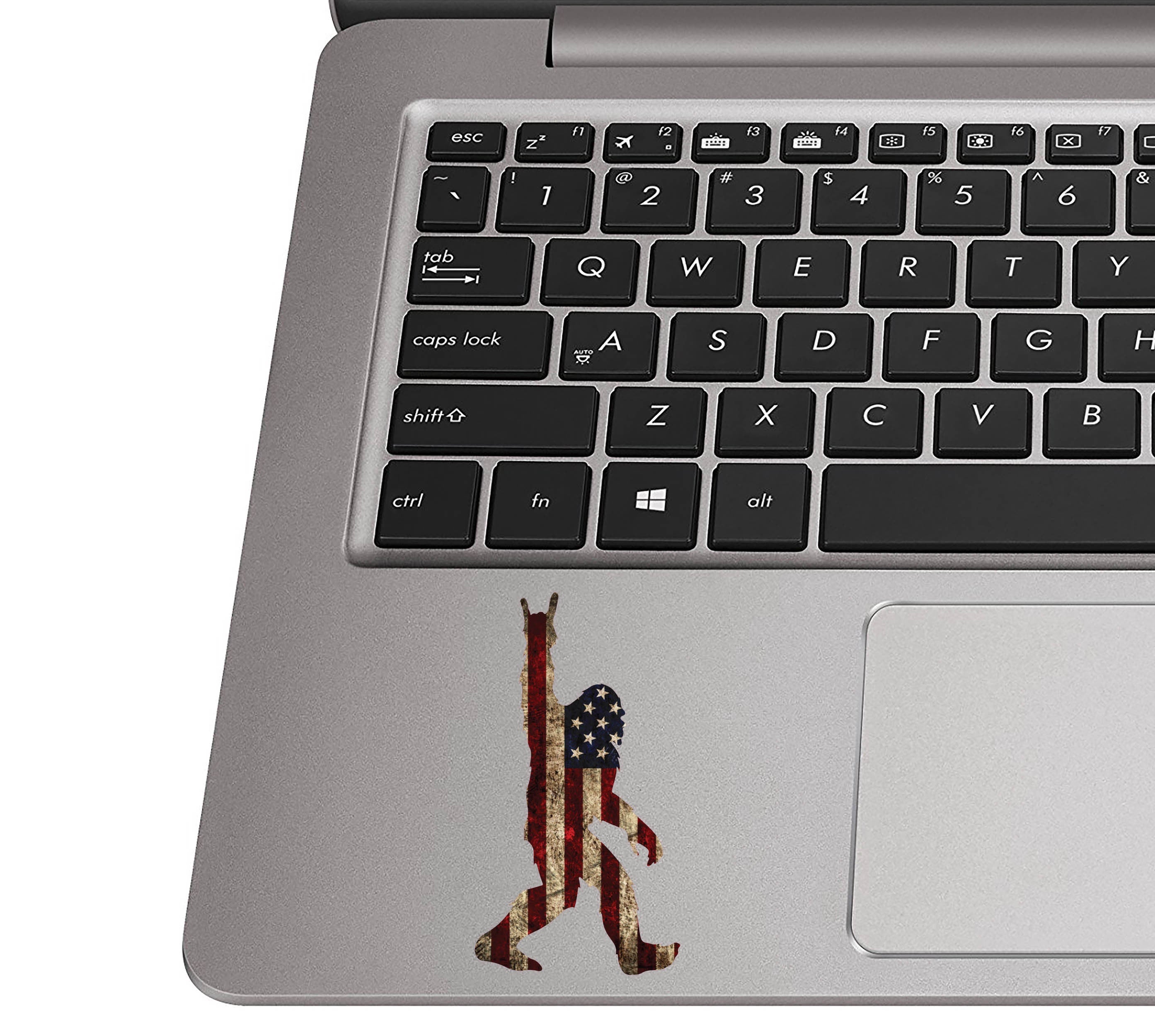 Rock On Sasquatch flag sticker on a silver laptop palm rest near a black QWERTY keyboard for scale view