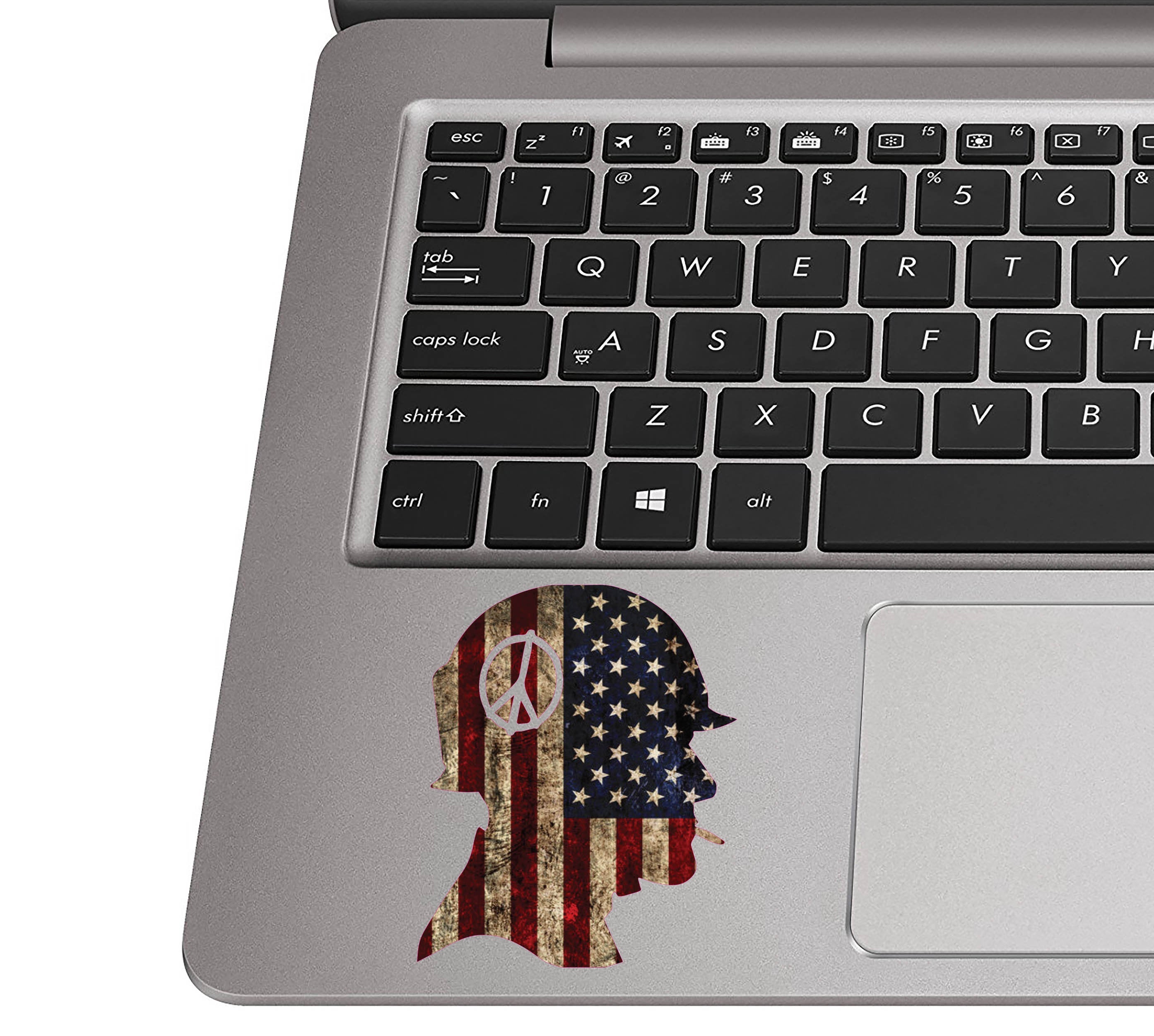 Rustic flag soldier helmet sticker on a silver laptop palm rest near a black QWERTY keyboard for sizing