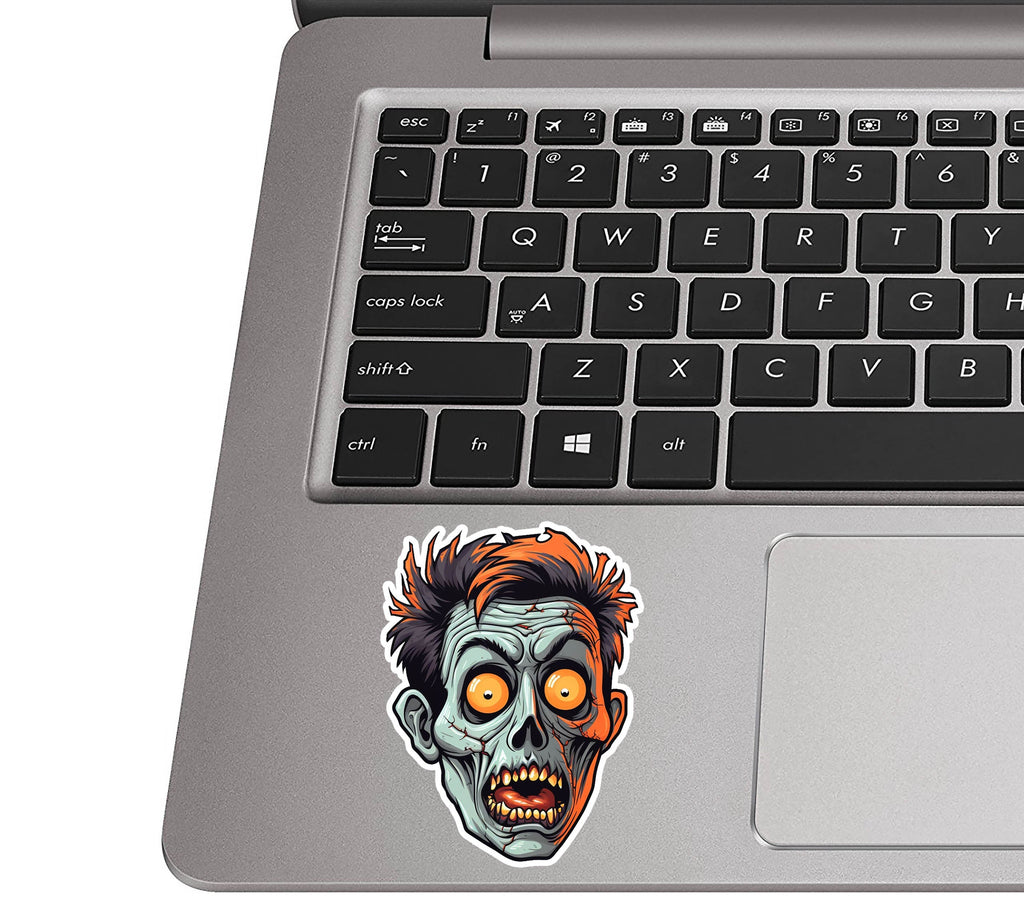 Halloween zombie head decal placed on a silver laptop palm rest near a black QWERTY keyboard for size scale