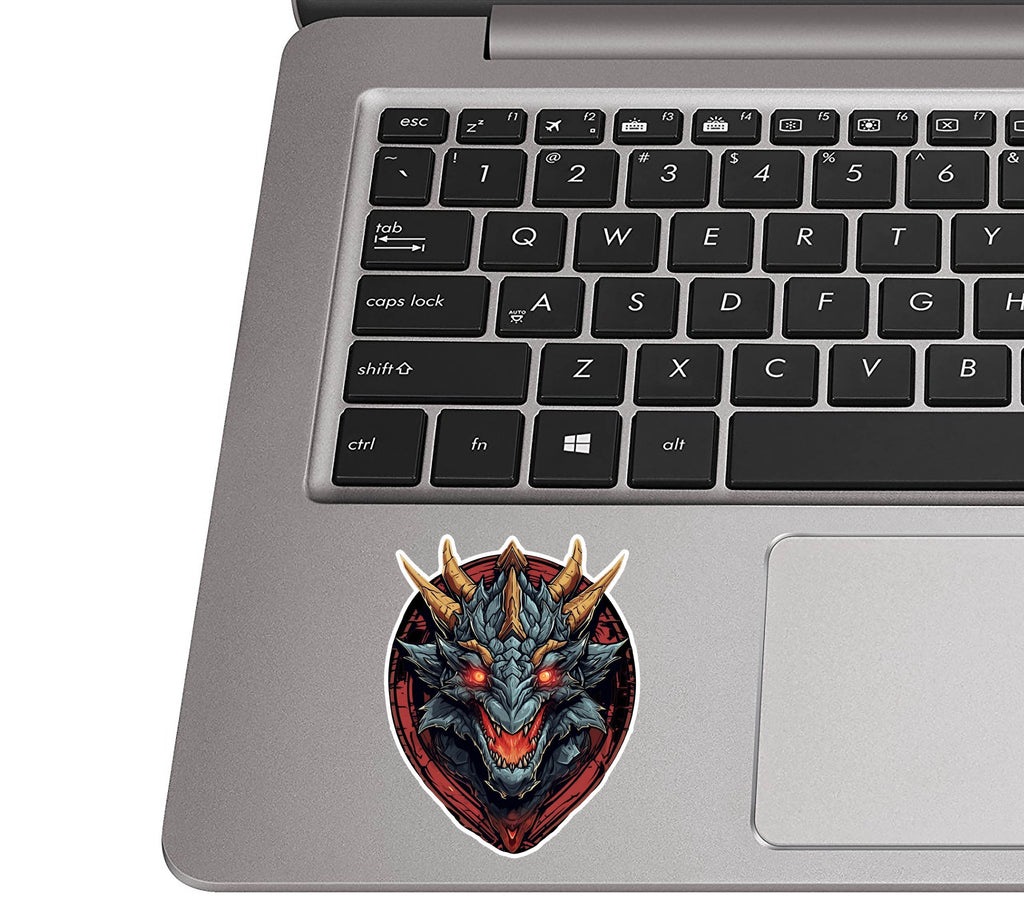 Black dragon head decal placed on a silver laptop palm rest beside a black QWERTY keyboard for size scale