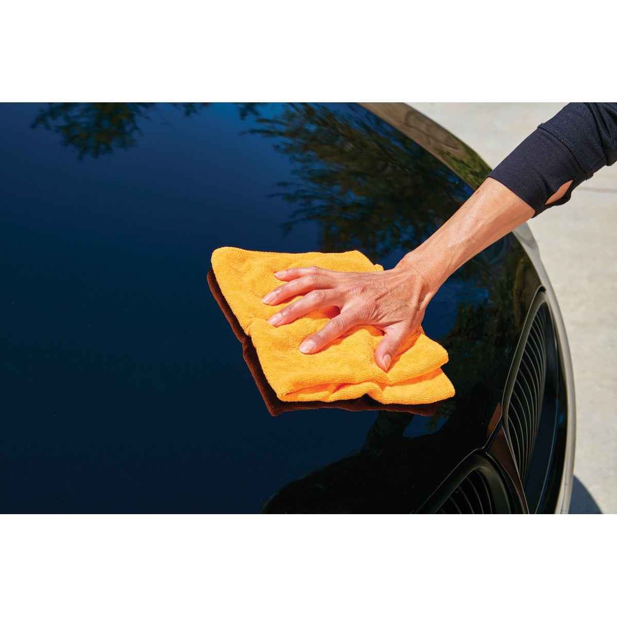 Hand wiping black car hood with orange microfiber cleaning cloth showing safe surface prep use