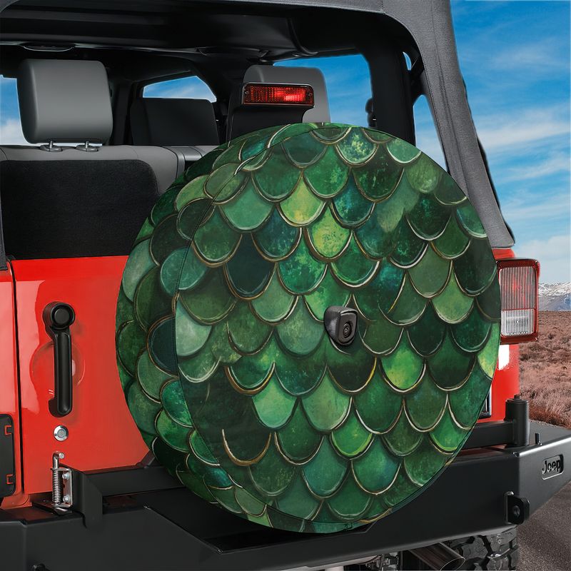 Green mermaid scale spare tire cover mounted on a red Jeep Wrangler tailgate with desert mountain backdrop