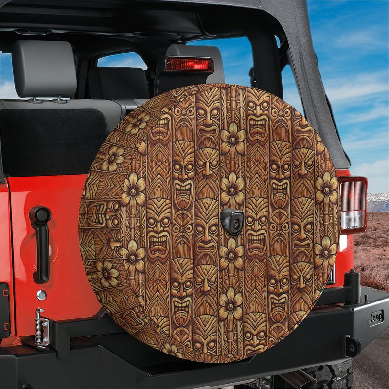 Tiki Wood Hawaiian carved face spare tire cover on red Jeep Wrangler with desert mountain horizon view