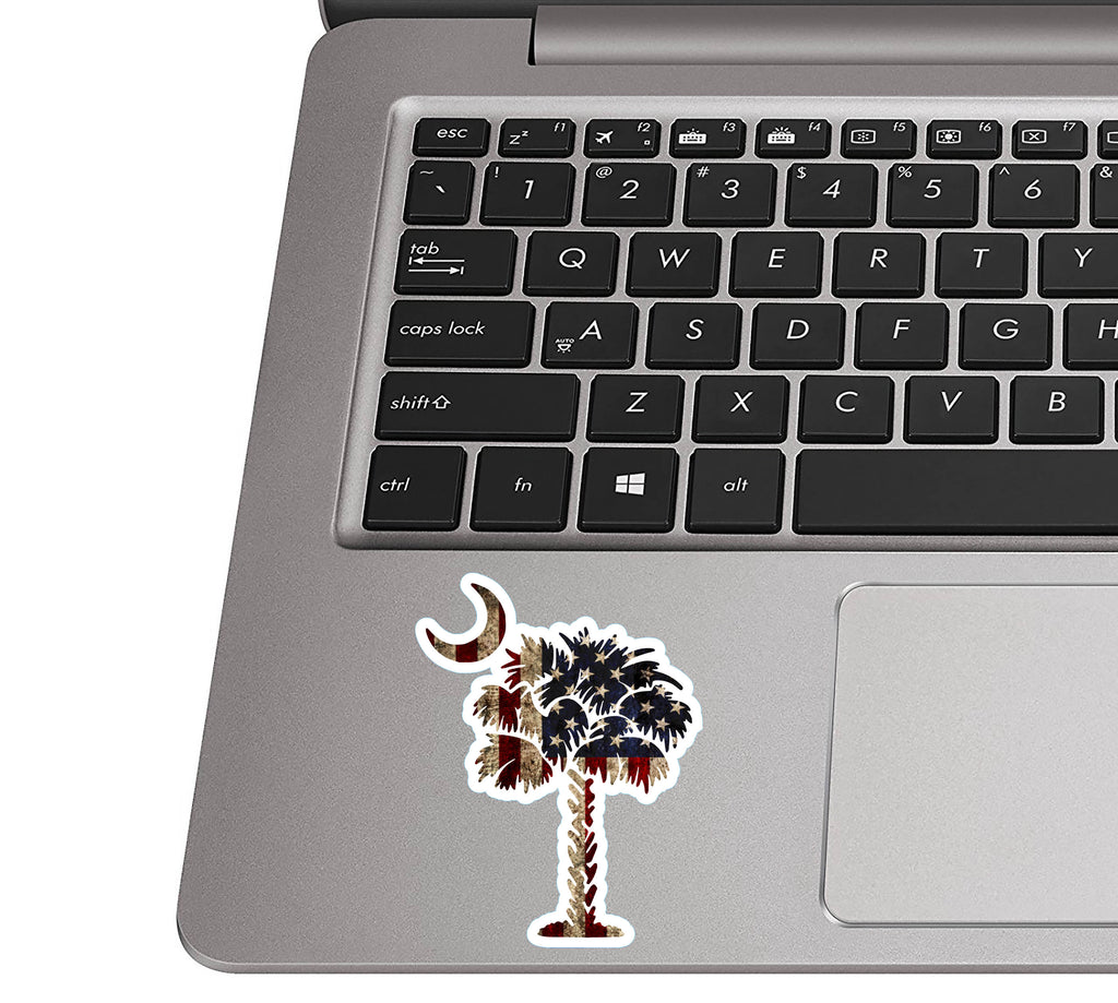 Rustic SC palmetto moon sticker on a silver laptop palm rest near a black QWERTY keyboard for scale